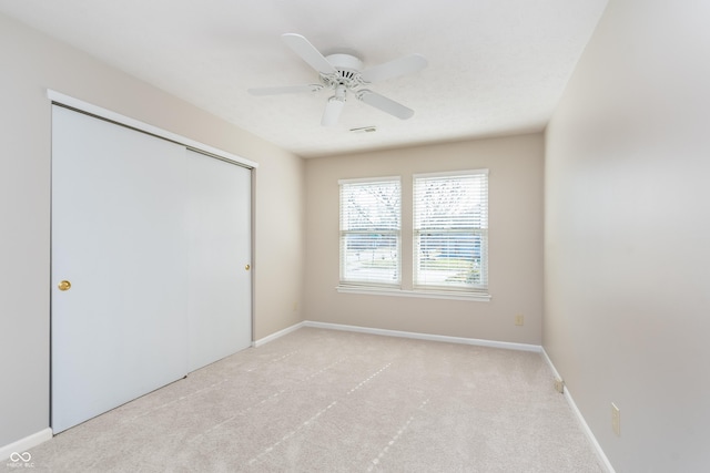 unfurnished bedroom featuring light colored carpet, visible vents, a closet, and baseboards