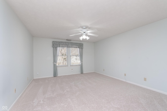 spare room with baseboards, light colored carpet, and a ceiling fan