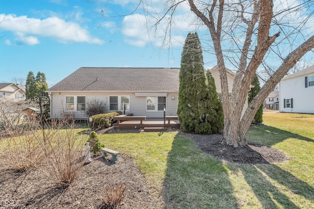 rear view of property featuring a wooden deck, a yard, and roof with shingles