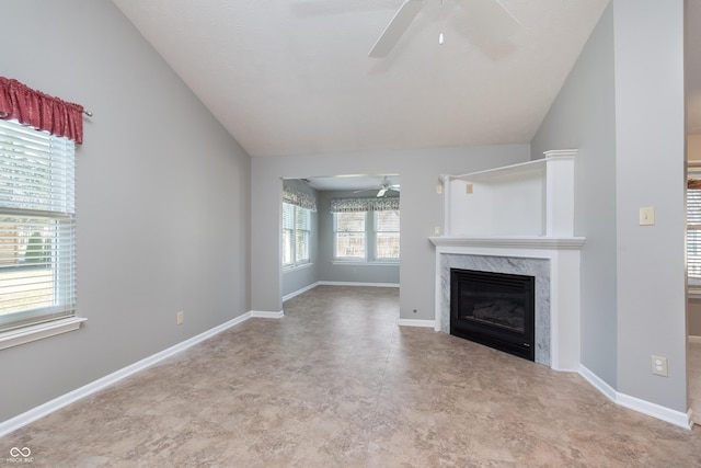 unfurnished living room with a premium fireplace, baseboards, ceiling fan, and vaulted ceiling