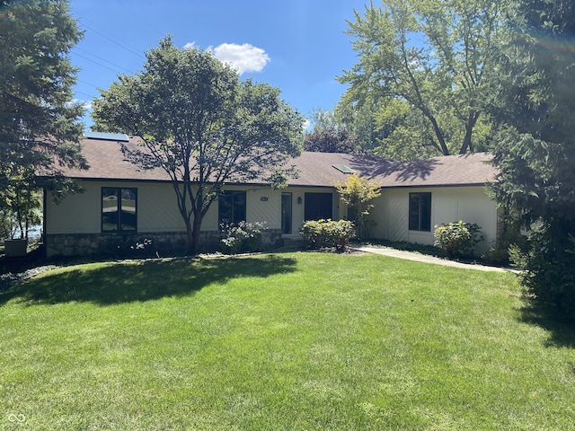 single story home with stone siding, a front yard, and a shingled roof