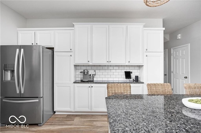 kitchen featuring light wood-type flooring, white cabinets, stainless steel fridge with ice dispenser, and dark stone counters