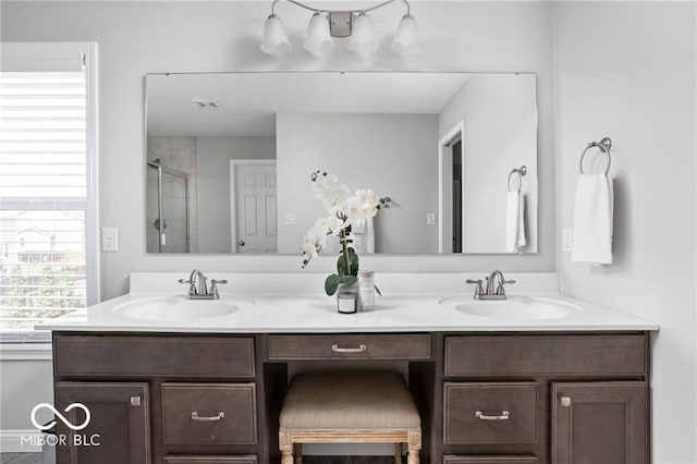 full bath featuring a sink, visible vents, a stall shower, and double vanity