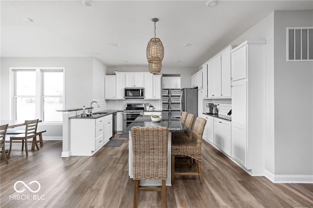 kitchen featuring dark wood finished floors, visible vents, a peninsula, and stainless steel appliances