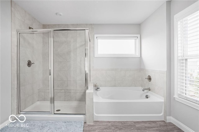 bathroom with a wealth of natural light, wood finished floors, a stall shower, and a bath