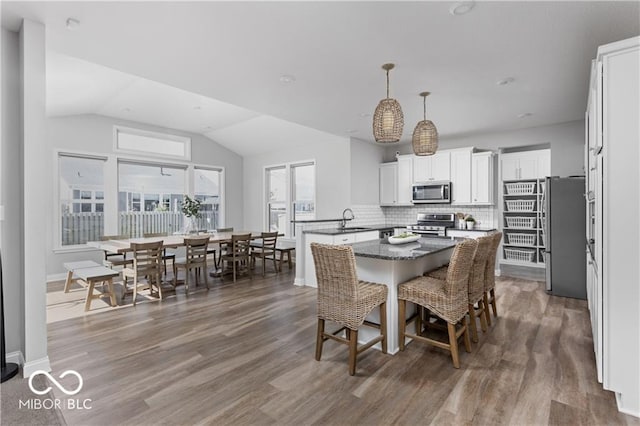 dining area with baseboards, wood finished floors, and vaulted ceiling