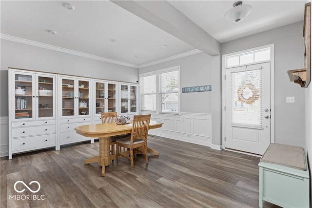 dining room featuring crown molding, dark wood-style floors, a wainscoted wall, and beam ceiling