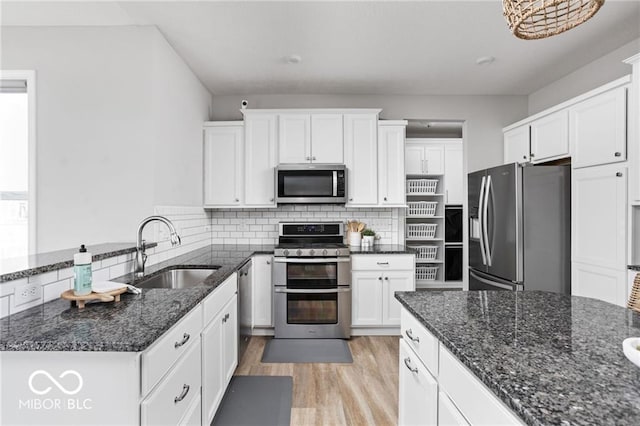 kitchen with a sink, stainless steel appliances, white cabinets, and decorative backsplash