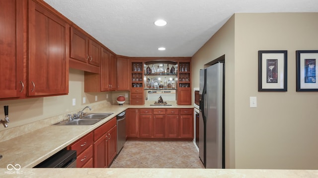 kitchen featuring a sink, open shelves, a textured ceiling, appliances with stainless steel finishes, and light countertops