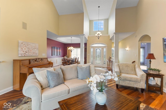 living room featuring arched walkways, a notable chandelier, baseboards, and wood finished floors