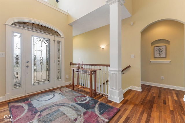 foyer with baseboards, arched walkways, and wood finished floors