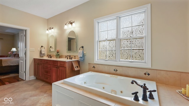 full bathroom with double vanity, a tub with jets, ensuite bath, and a sink