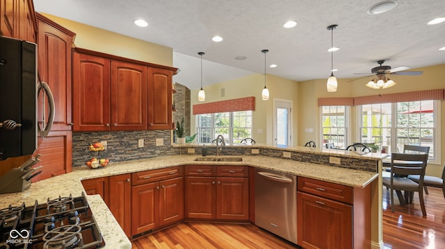 kitchen with a ceiling fan, light stone countertops, a sink, black gas cooktop, and stainless steel dishwasher