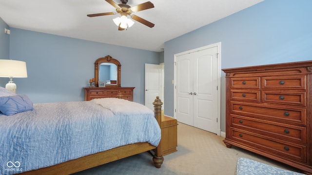 bedroom featuring a closet, light colored carpet, and a ceiling fan