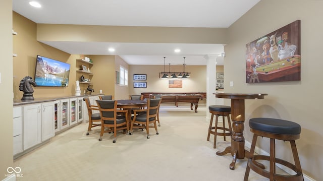 dining area featuring bar, recessed lighting, baseboards, light colored carpet, and ornate columns