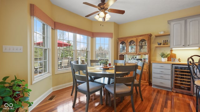 dining room featuring visible vents, plenty of natural light, beverage cooler, and dark wood finished floors