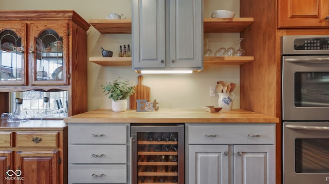 kitchen with open shelves, wooden counters, double oven, and beverage cooler