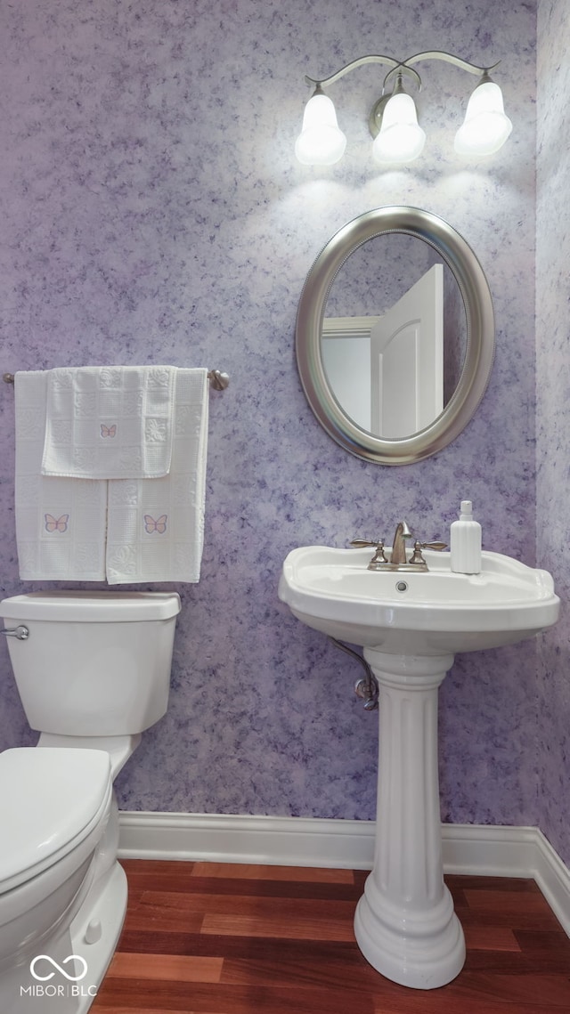 bathroom featuring wallpapered walls, baseboards, and wood finished floors