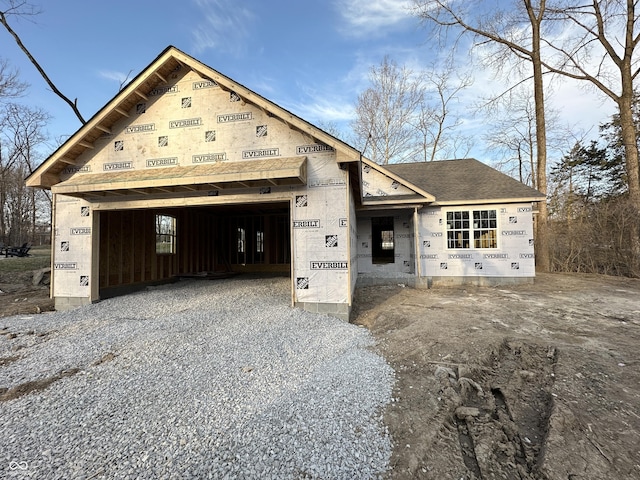 unfinished property with a garage, driveway, and a shingled roof