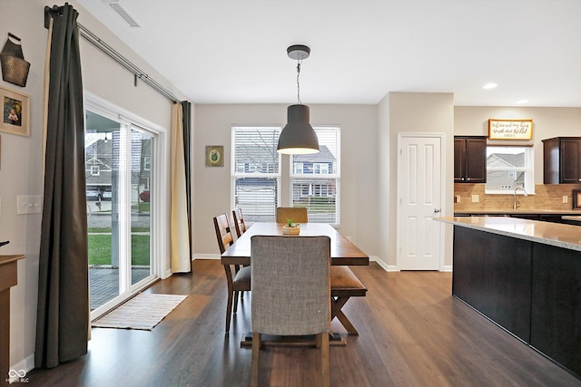 dining area with dark wood-type flooring, visible vents, baseboards, and a wealth of natural light