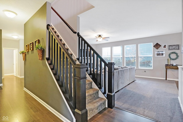 staircase featuring wood finished floors, baseboards, and ceiling fan