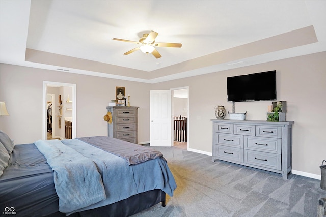 bedroom with light carpet, a raised ceiling, and baseboards