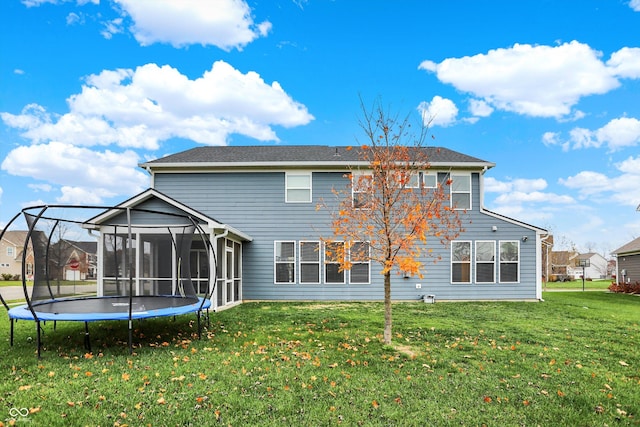 back of property with a trampoline, a yard, and a sunroom