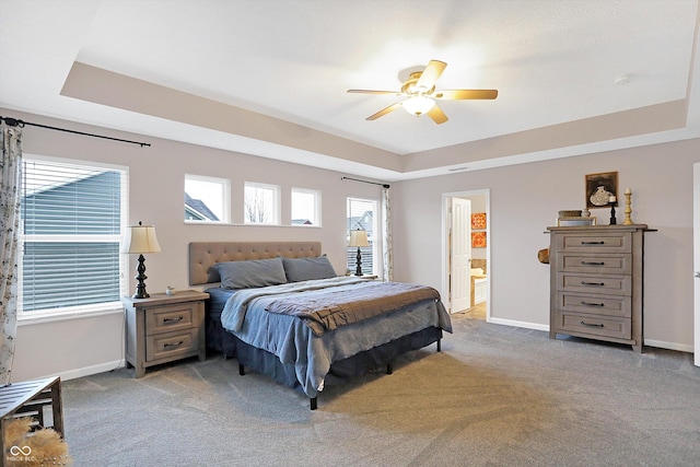 bedroom featuring a tray ceiling, light colored carpet, and baseboards