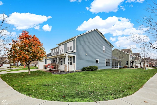 view of side of home featuring driveway, a yard, a residential view, covered porch, and an attached garage