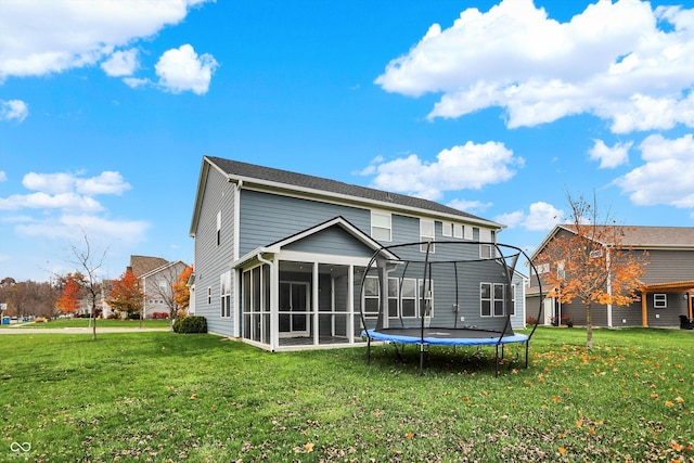 back of property featuring a trampoline, a lawn, and a sunroom