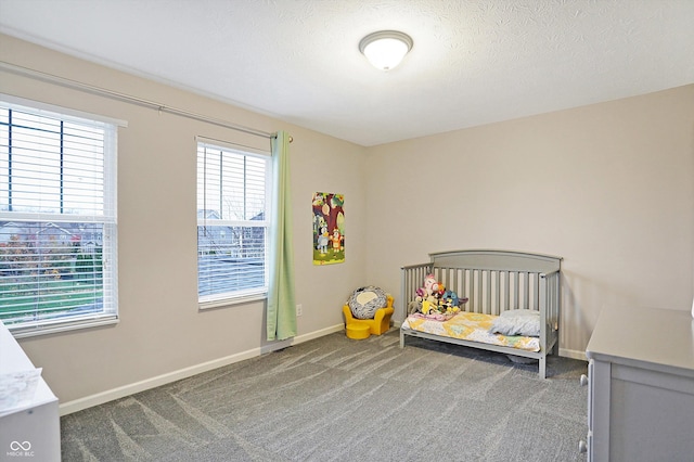 carpeted bedroom featuring a crib, a textured ceiling, and baseboards