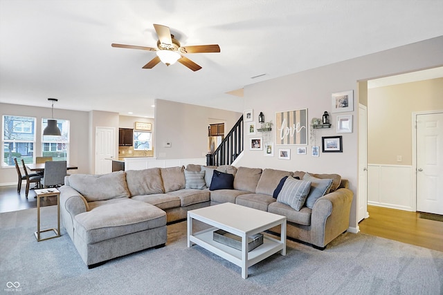 living area featuring stairway, wood finished floors, and ceiling fan