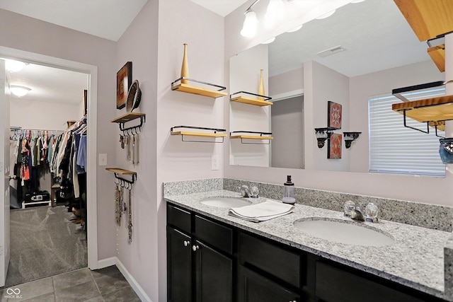 bathroom featuring a walk in closet, double vanity, visible vents, and a sink