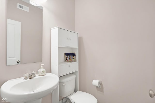 bathroom featuring toilet, visible vents, and a sink