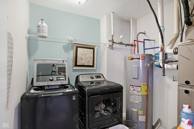 washroom featuring laundry area, a textured ceiling, water heater, and washing machine and clothes dryer