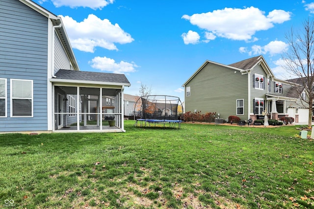 rear view of house featuring a lawn, a sunroom, a trampoline, a shingled roof, and central AC unit