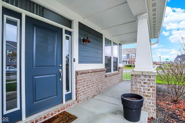 doorway to property featuring brick siding and covered porch