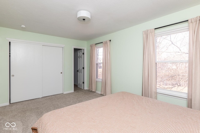 carpeted bedroom featuring a closet and baseboards