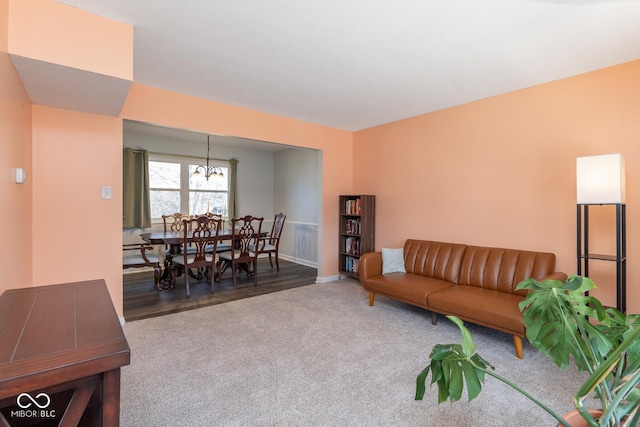 carpeted living area featuring baseboards and an inviting chandelier