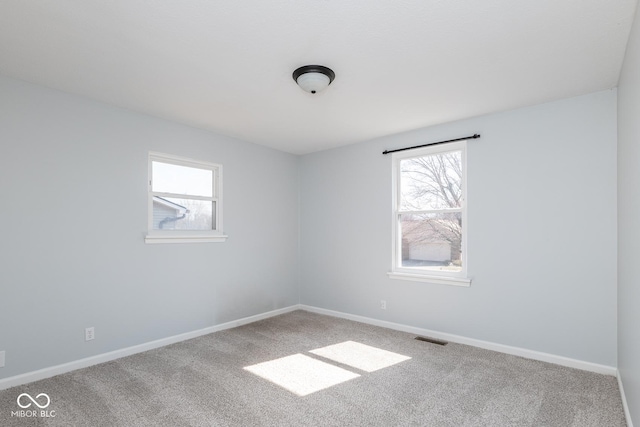 spare room featuring carpet flooring, baseboards, and visible vents