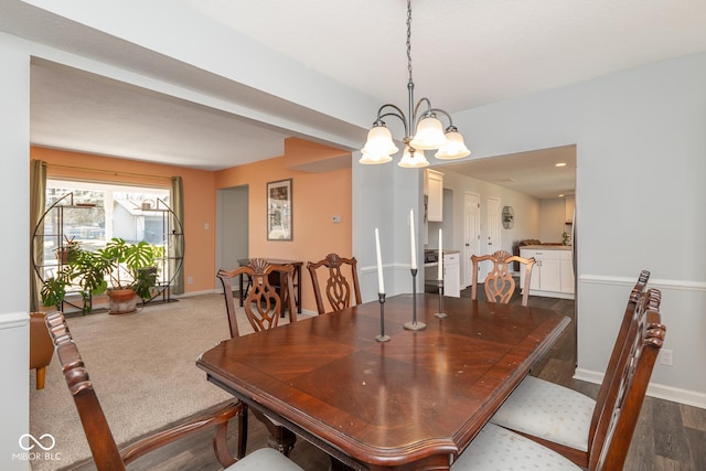 dining area with dark colored carpet, baseboards, and a notable chandelier