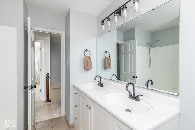 bathroom featuring a sink, a shower, double vanity, and tile patterned floors