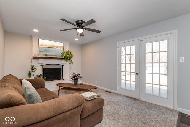 living room featuring visible vents, carpet floors, baseboards, a fireplace, and french doors