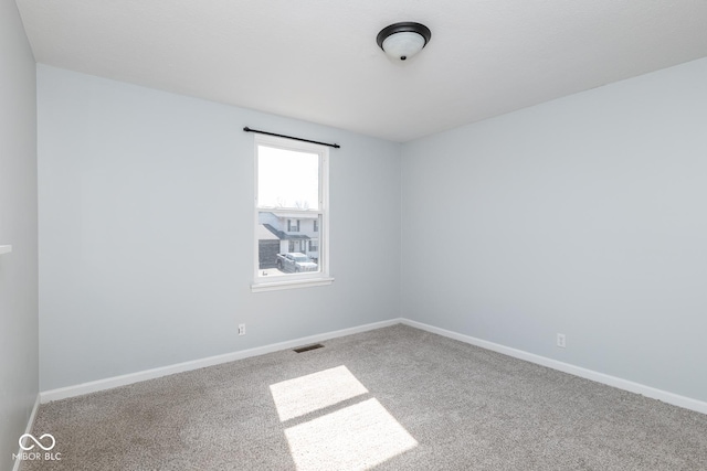 carpeted spare room with visible vents and baseboards