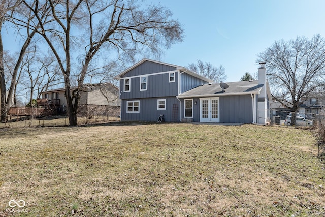 back of house featuring french doors, a lawn, a fenced backyard, and a chimney