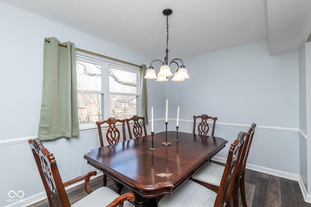 dining space featuring a notable chandelier, a textured ceiling, dark wood-type flooring, and baseboards