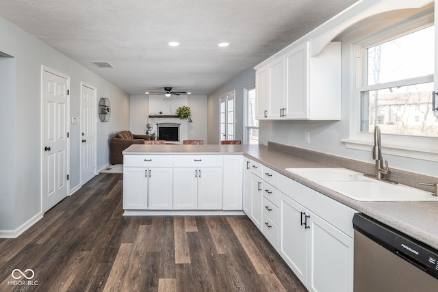 kitchen featuring a sink, dark wood-style floors, a peninsula, a fireplace, and dishwasher