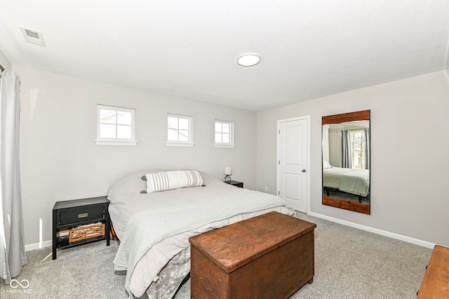 bedroom with multiple windows, light colored carpet, visible vents, and baseboards