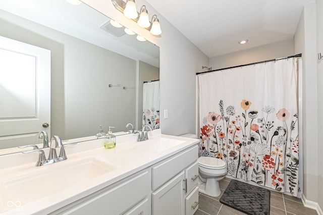 bathroom with a sink, toilet, double vanity, and tile patterned flooring