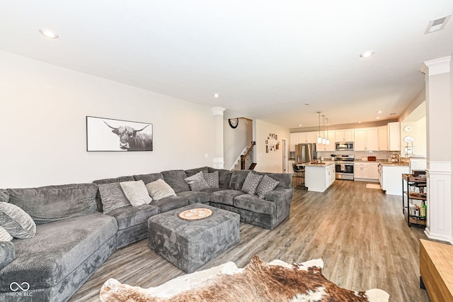 living room featuring recessed lighting, visible vents, light wood-style flooring, and stairs